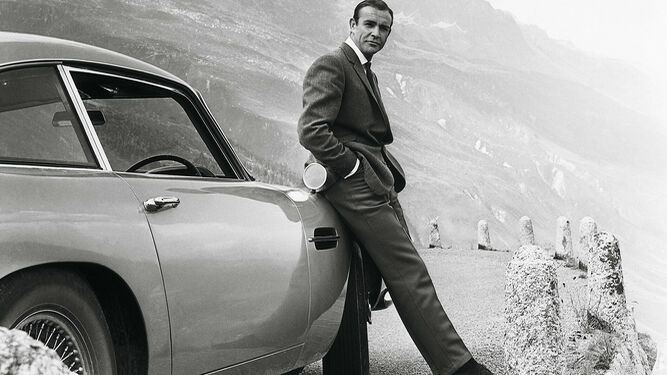 Imagen del agente secreto 007 apoyado en uno de sus coches Aston Martin.
