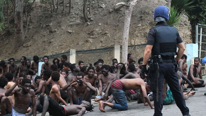 Un policía ante algunos de los 153 migrantes que han sorteado la valla de Ceuta este viernes.