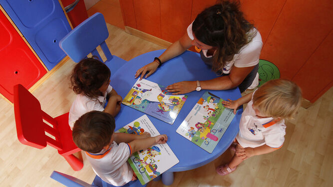 La maestra de la escuela infantil 'El Ratón Pérez' atiende a los niños en su primer día de clase.