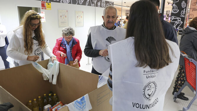 Varios voluntarios entregan bolsas en el supermercado Maskom para la gran recogida de alimentos.