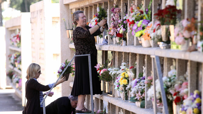 Varias mujeres ponen flores en un cementerio.