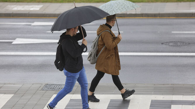 Dos jóvenes con paraguas en Málaga capital.