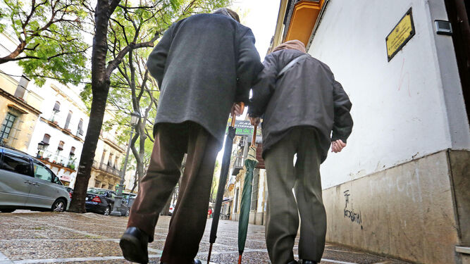 Dos personas mayores paseando por la calle.