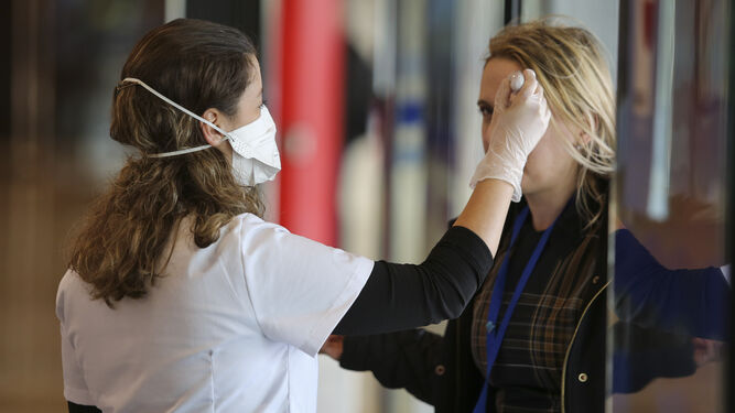 Una de las enfermeras toma la temperatura a una mujer a la entrada al congreso de robótica en Málaga.