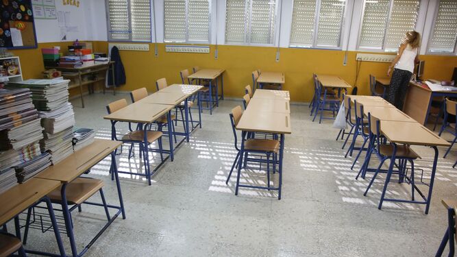 Una docente cierra las persianas en un aula vacía.