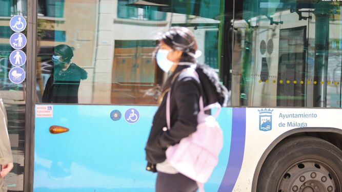 Una mujer con mascarilla pasa por delante de un autobús de la EMT.