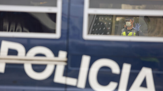 Un policía nacional con mascarilla da el alto a un vehículo