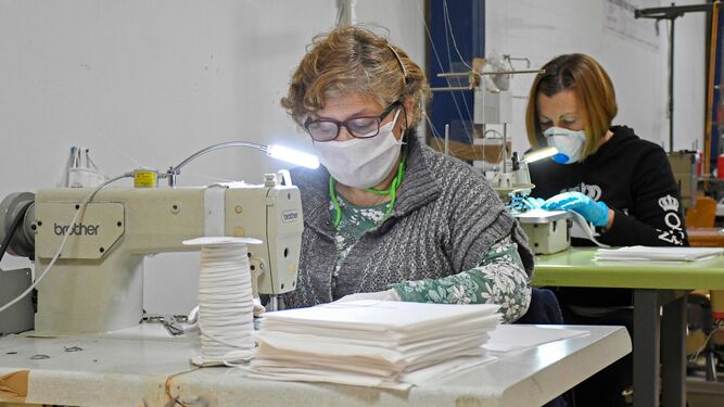 Dos mujeres elaborando mascarillas solidarias en un taller de costura.
