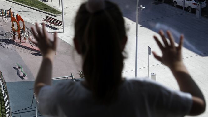 Una niña observa un parque desde una ventana.