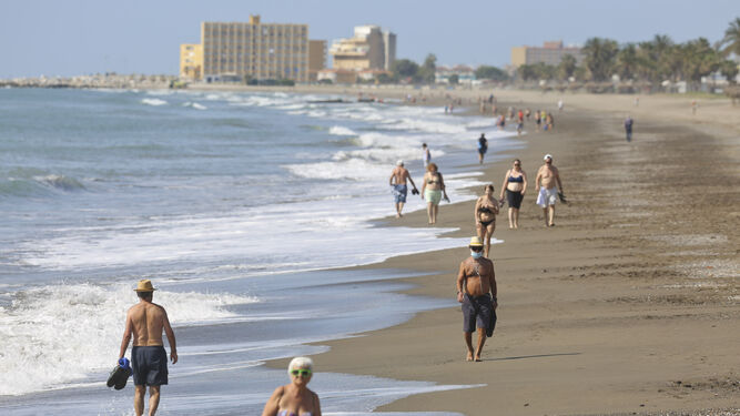 Varias personas caminan por la playa, en Málaga.