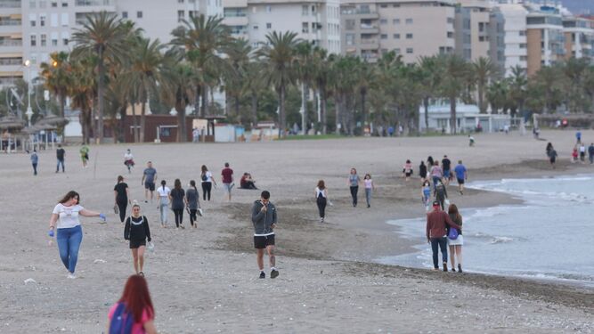 Varias personas pasean por la playa en Málaga capital.