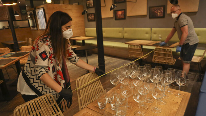 Trabajadores de un bar miden la distancia de seguridad entre mesas.
