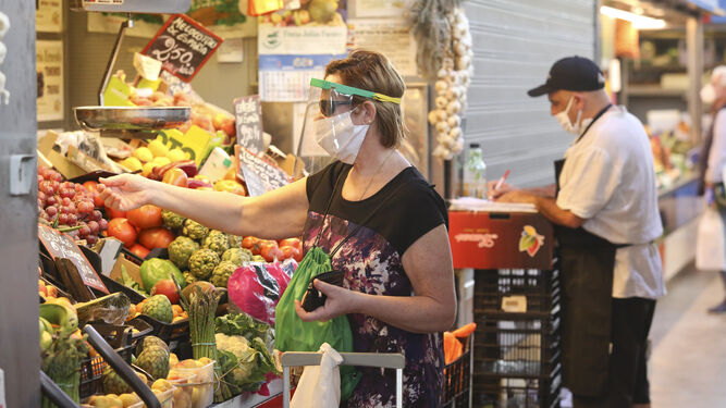 Una mujer compra en un puesto de frutas en un mercado andaluz en plena pandemia.