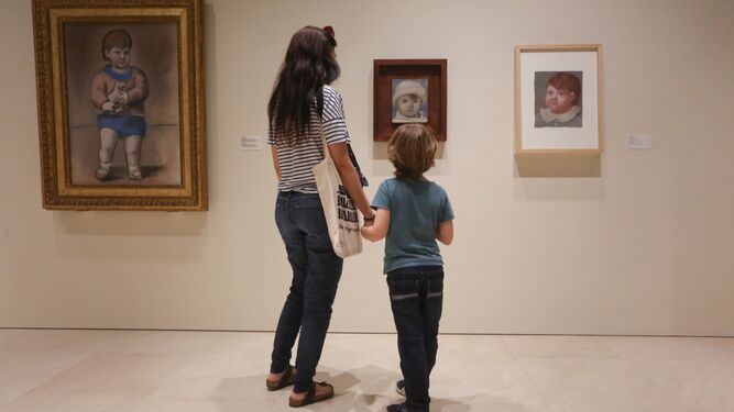Dos visitantes observan 'Retrato de Paulo con gorro blanco' (1923), en la colección permanente del Museo Picasso Málaga.