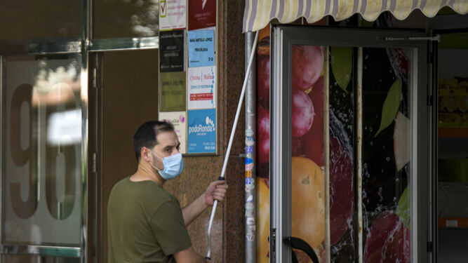 Un comerciante abre la persiana de su establecimiento