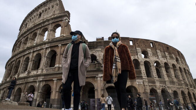 Dos turistas con mascarillas frente al coliseo de Roma.