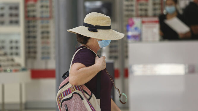 Una mujer con sombrero y mascarilla pasea por Málaga