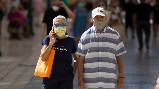 Una pareja camina por la calle Larios de Málaga.