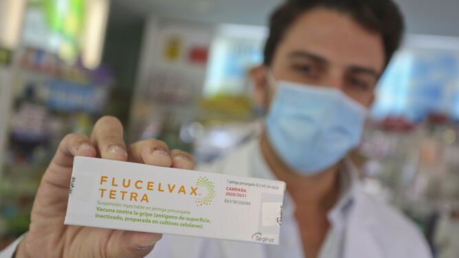 Un sanitario de una farmacia muestra una de las pocas vacunas de la gripe que han llegado a las boticas malagueñas.