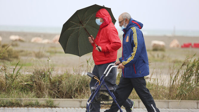 Dos personas, en el paseo marítmo de Huelin, se protegen de la lluvia.