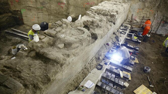 Varios operarios intervienen sobre el trozo de muralla de los siglos XII-XIII encontrado en la obra del Metro de Málaga.