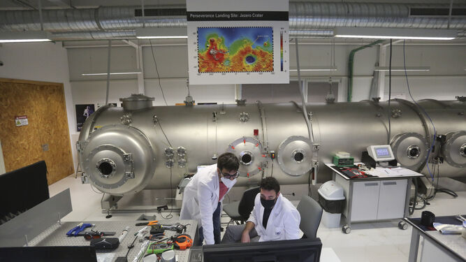 Dos investigadores trabajan en el UMA Laserlab con la cámara a sus espaldas.