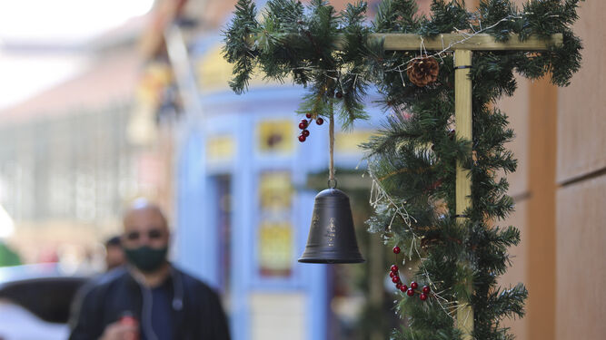 Un hombre pasa por delante de un comercio con decoración navideña en Málaga.