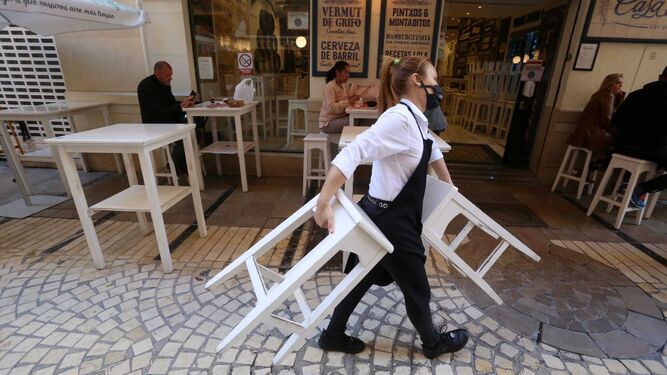Una trabajadora recoge la terraza de un establecimiento de hostelería de Málaga capital.
