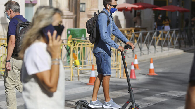 Un usuario de patinete eléctrico en un paseo de peatones.