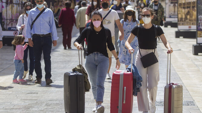Varios turistas pasan con sus maletas por calle Larios, en Málaga capital.