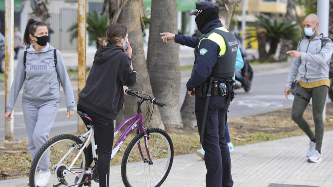 Una ciclista, en el Paseo Marítimo Pablo Ruiz Picasso, parada por un policía local.