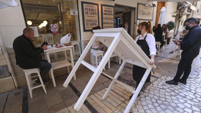 Una camarera retira una mesa de un bar del Centro de Málaga.