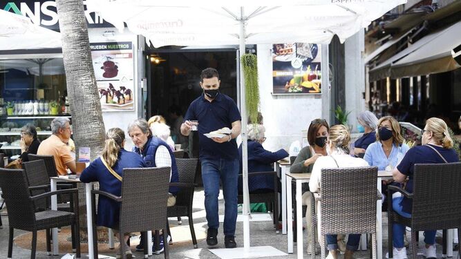 Un camarero atiende la terraza de un establecimiento de hostelería en Málaga.