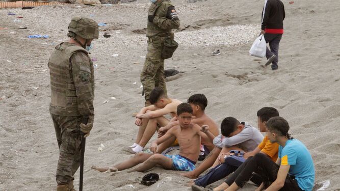Miembros del Ejército de Tierra vigilan a un grupo de inmigrantes menores que lograron cruzar uno de los espigones fronterizos de Ceuta  la semana pasada.