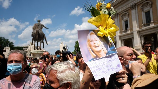 Italianos por las calles de Roma este viernes portando fotos de Raffaella Carrá y flores en su honor.