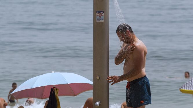 Un hombre se refresca en una ducha, este sábado, en una playa de Málaga capital.
