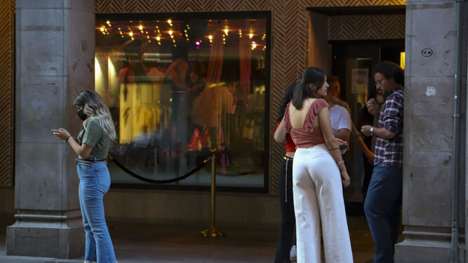 Dos jóvenes esperan la cola para entrar en una discoteca de Granada.