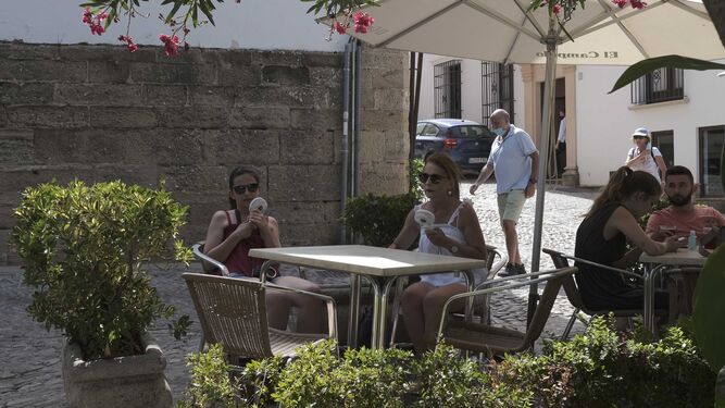 Dos turistas sentadas en una terraza de Ronda, con pequeños ventiladores.