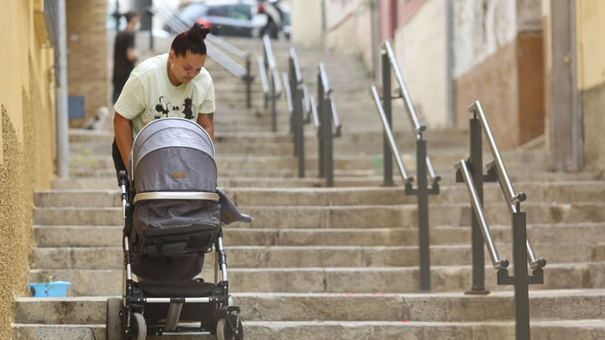 Una mujer sube el carrito de su hija por las escaleras