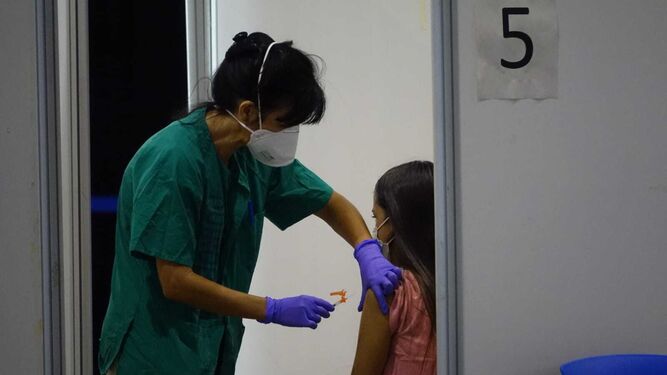 Una sanitaria pone la vacuna del Covid a una joven.