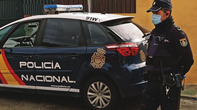 Un agente junto a un coche de la Policía Nacional.