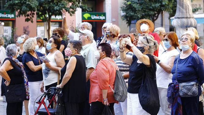 Turistas atienden las explicaciones de un guía en la puerta de la Catedral de Málaga.