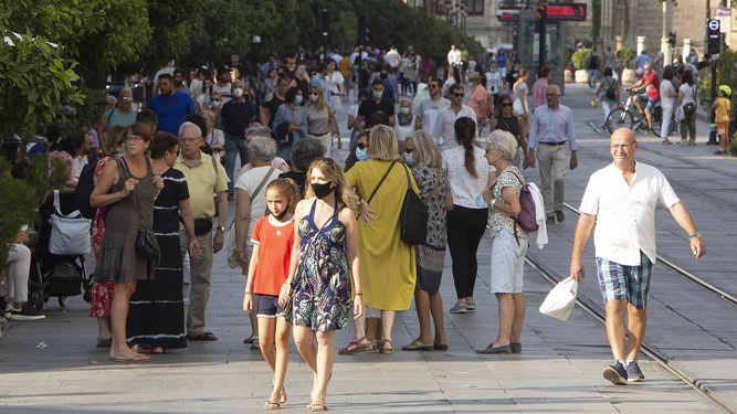 Gente con y sin mascarilla por la Avenida de la Constitución de Sevilla.