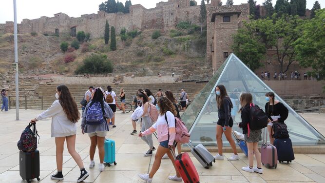 Varios turistas con maletas frente al Teatro Romano de Málaga.