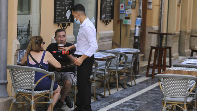 Un camarero atiende a unos clientes en el centro de Málaga