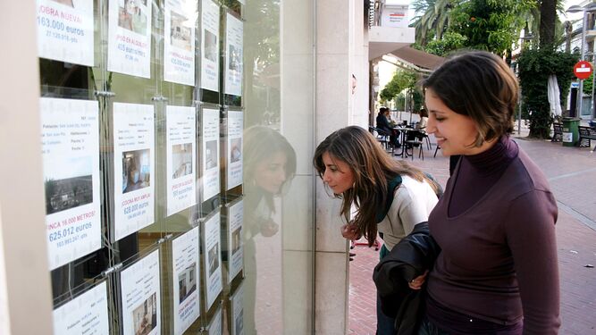 Dos jóvenes miran los anuncios de una inmobiliaria.