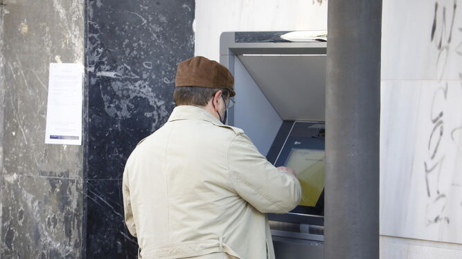 Persona mayor sacando dinero en un cajero automático.