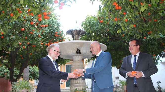 Joe Cooper recoge las naranjas del Alcázar que le ofrece Antonio Muñoz, en presencia de Juan Carlos Cabrera.
