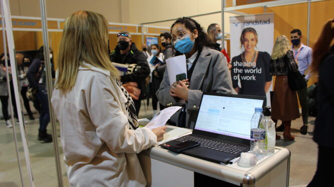 Una joven entrega su currículum en un expositor de la Feria de empleo de Marbella.