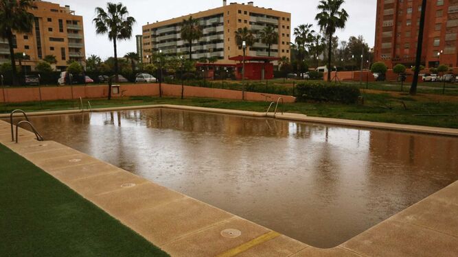 La piscina de una urbanización en Málaga completamente llena de barro.
